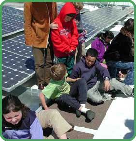 Students sitting next to solar panels