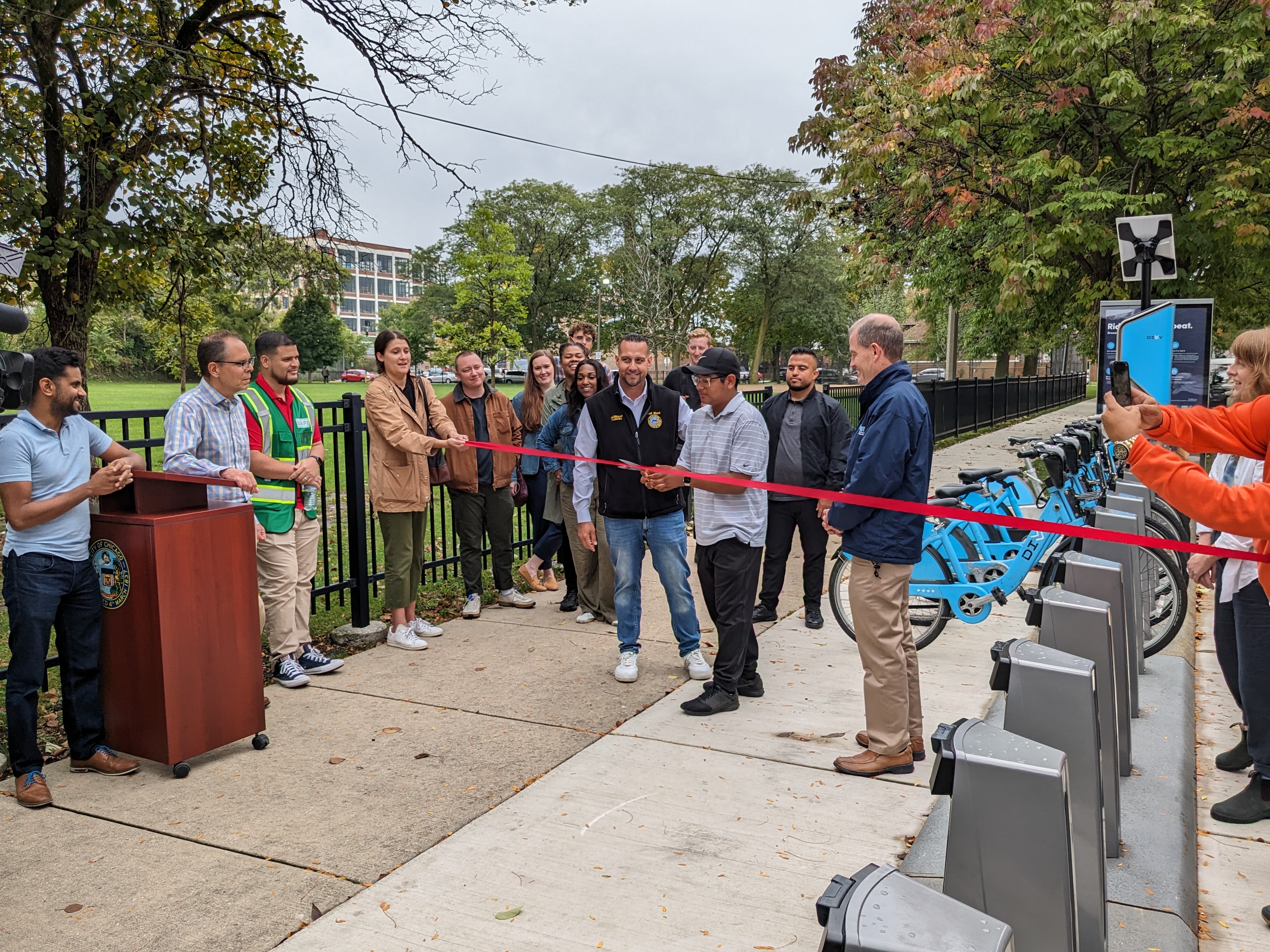 A resident cuts a ceremonial ribbon in front of a new Divvy station