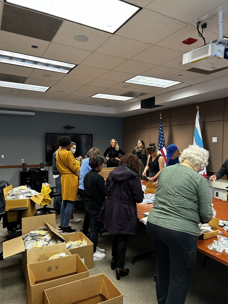 Volunteers around a table packing Narcan and other supplies into harm reduction bags