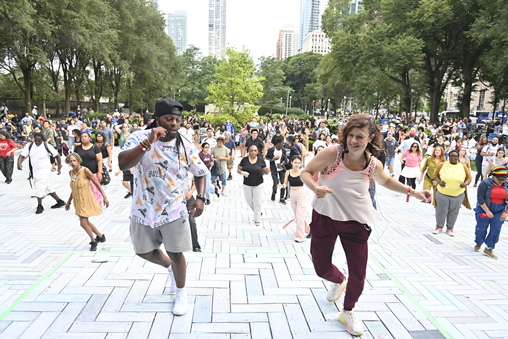 Chicago SummerDance (Dance instructors teaching dance moves on a dance floor in a park with participants dancing in the background)