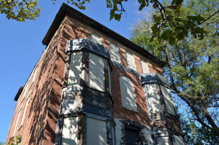 Front view of brick building with green tree framing the exterior