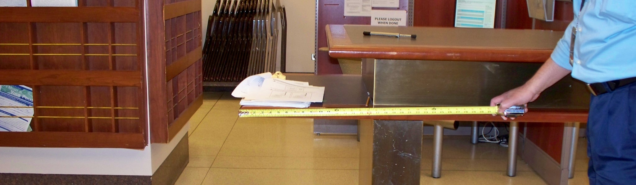 An inspector measures a booth's knee space for compliance. An inspector measures a booth's knee space for compliance.