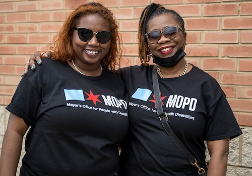Two women posing for a photo wearing t-shirts with MOPD Logo on them