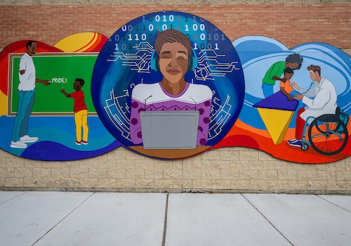 Mural on the Central West Community Center with three different images. On the left of the mural shows a brown skin man with a loss limb holding a piece of chalk to a chalk board spelling out the words pride. In that same image is a young brown skin boy in a red shirt and yellow pants holding chalk to the chalk board. In the center of the mural is a brown skin male with a white and purple sweater wearing blue headphones and a laptop computer in front of him. His eyes are closed and behind him are calculations. On the right of the mural are a three people, a brown skin woman with a young brown skin child on a blue and yellow hospital table. There is a light tan man in a wheel chair with a lap coat on holding a stethoscope to the chest of the young brown skin boy