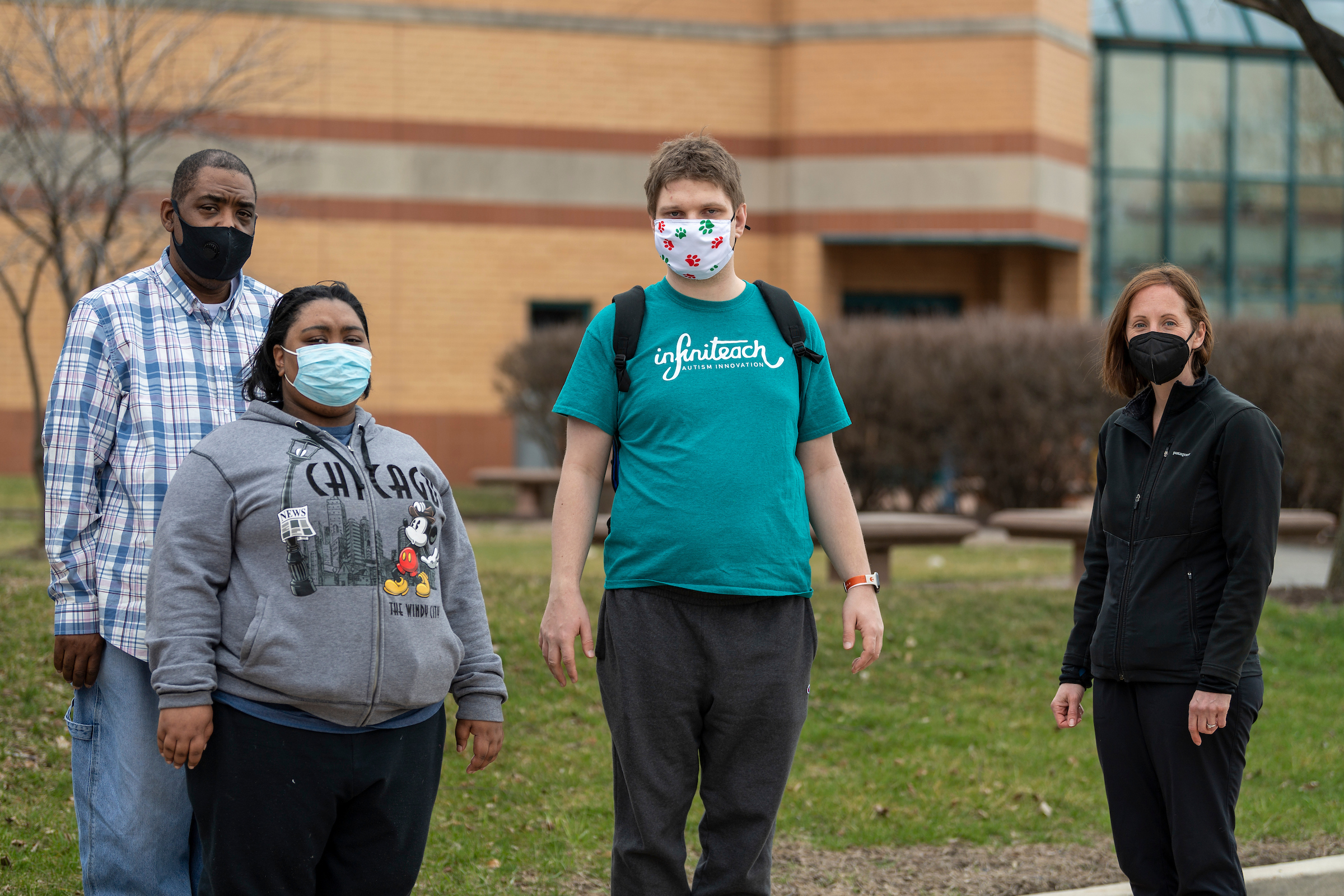 Four people wearing masks waiting to get a COVID-19 vaccine
