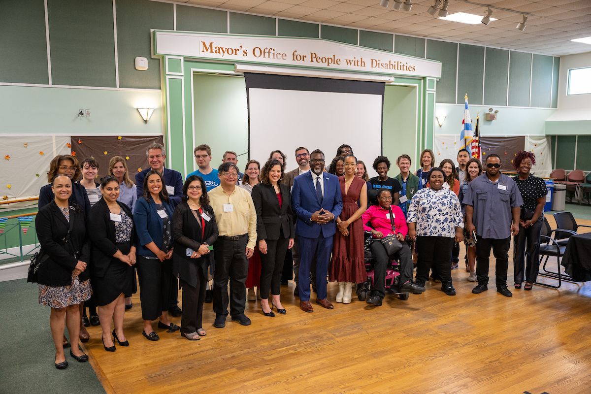 Job seekers at the MOPD Career Center stand with Mayor Brandon Johnson, in a blue suit, for an event marking National Disability Employment Awareness Month in 2023. 