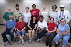 A group of senior sitting in a room on chairs posing for a picture