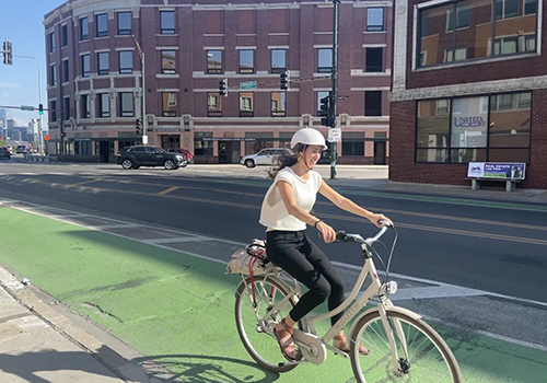 Person biking in green bike lane with building in background