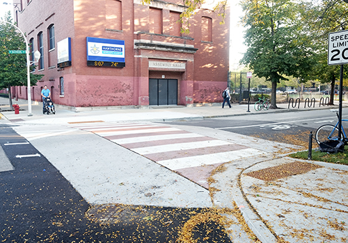 Raised crosswalk  with an adult pushing a stroller approaching