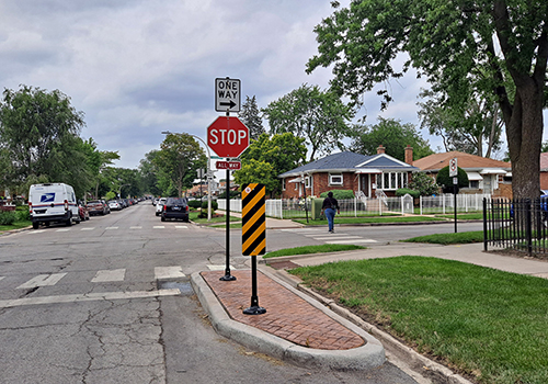 view of an intersection with a stop sign an a concrete bumpout detached from the curb next to the crosswalk