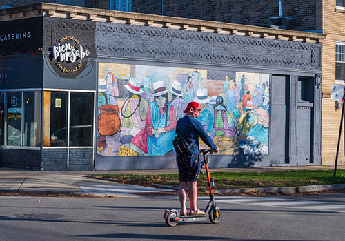 Person riding a stand up motorized scooter in the street crossing through an intersection