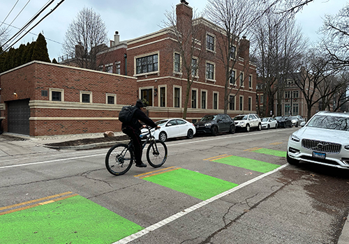 Person riding bike on street with green pavement markings visible