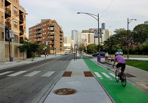 CTA bus stopped at bus stop with a concrete bus boarding island separating the travel lane from green painted bike lane.
