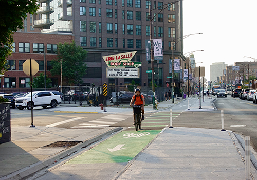 person riding bike waiting at protected intersection