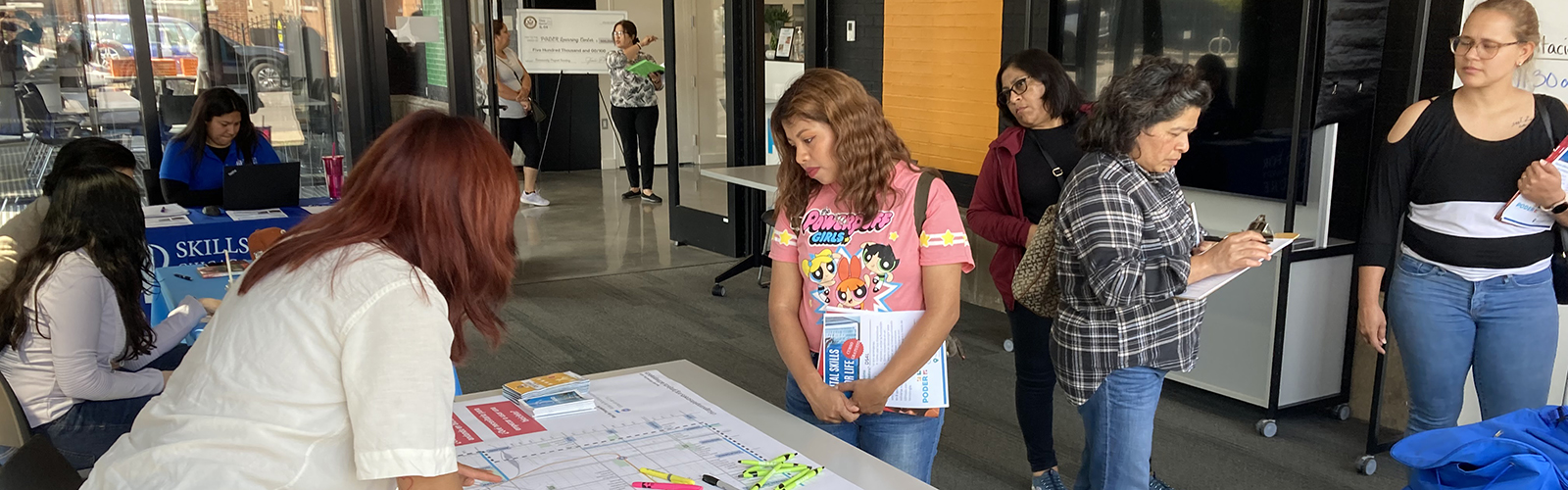 Person standing next to table with printed neighborhood map displayed on it