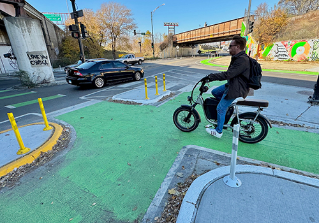 person riding bike waiting at protected intersection