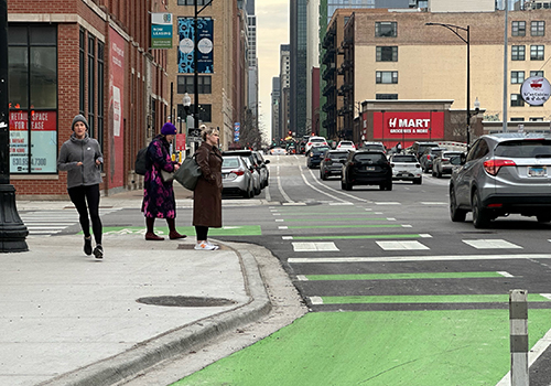 CTA bus stopped at bus stop with a concrete bus boarding island separating the travel lane from green painted bike lane.