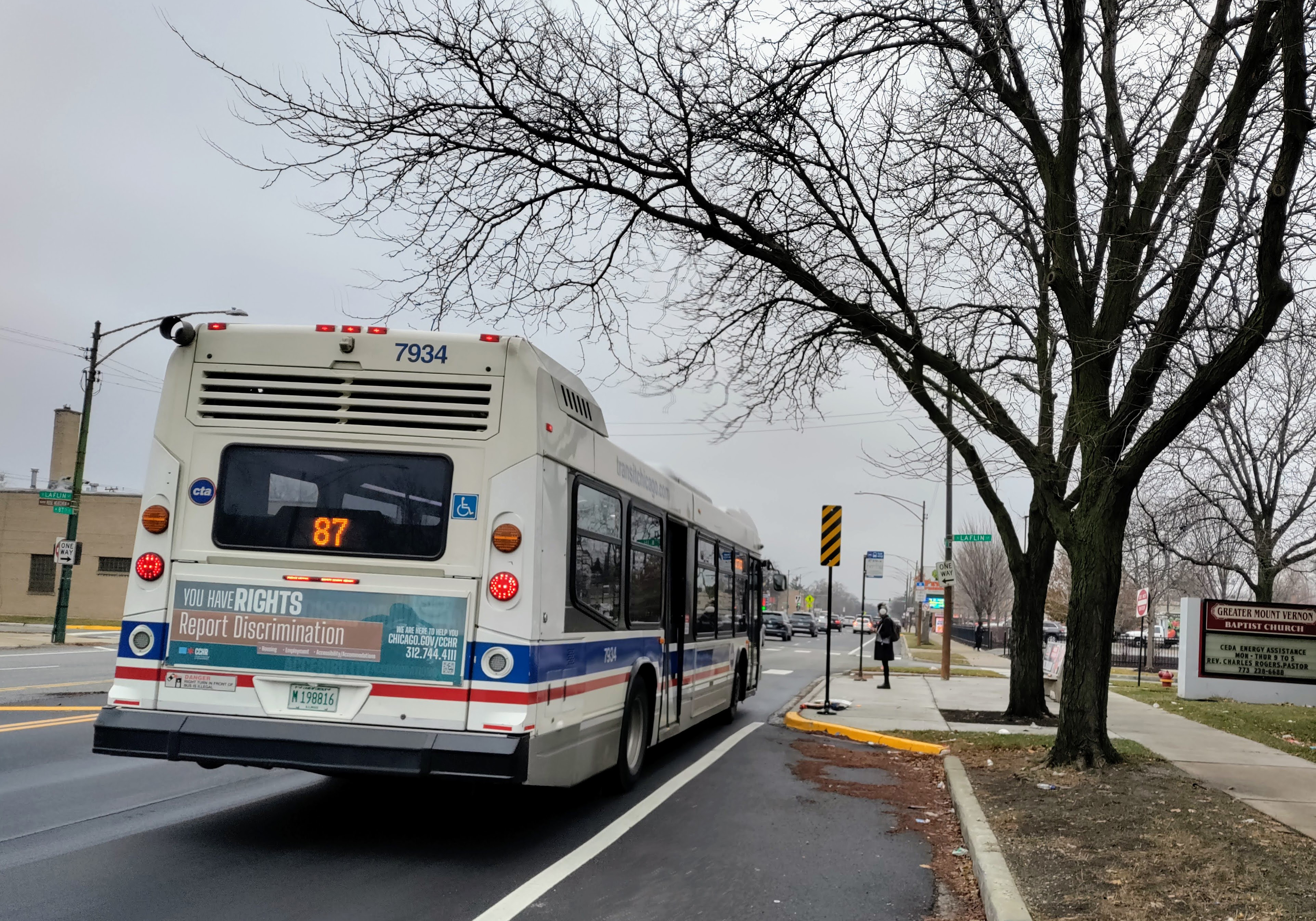 bus stopped in roadway with bus boarding island and person waiting to board