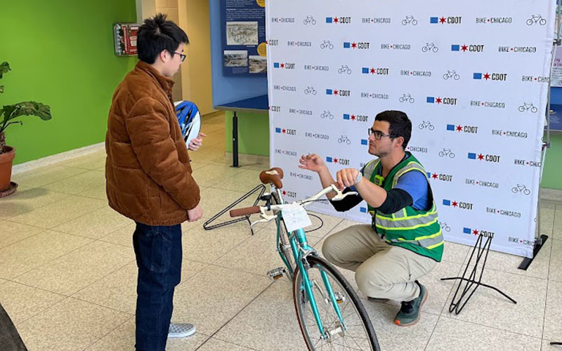 SAFE Ambassador crouching next to bike at bike chicago giveaway event talking to the recipient of the free bike