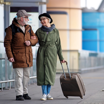 Elderly couple traveling together, pulling rolling suitcase