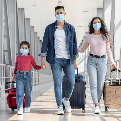 masked mother, father, and child traveling together, pulling rolling suitcases