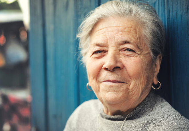 elderly woman smiling against a blue wall
