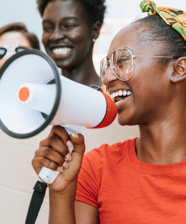 Photo of a young, smiling woman holding a megaphone to her mouth