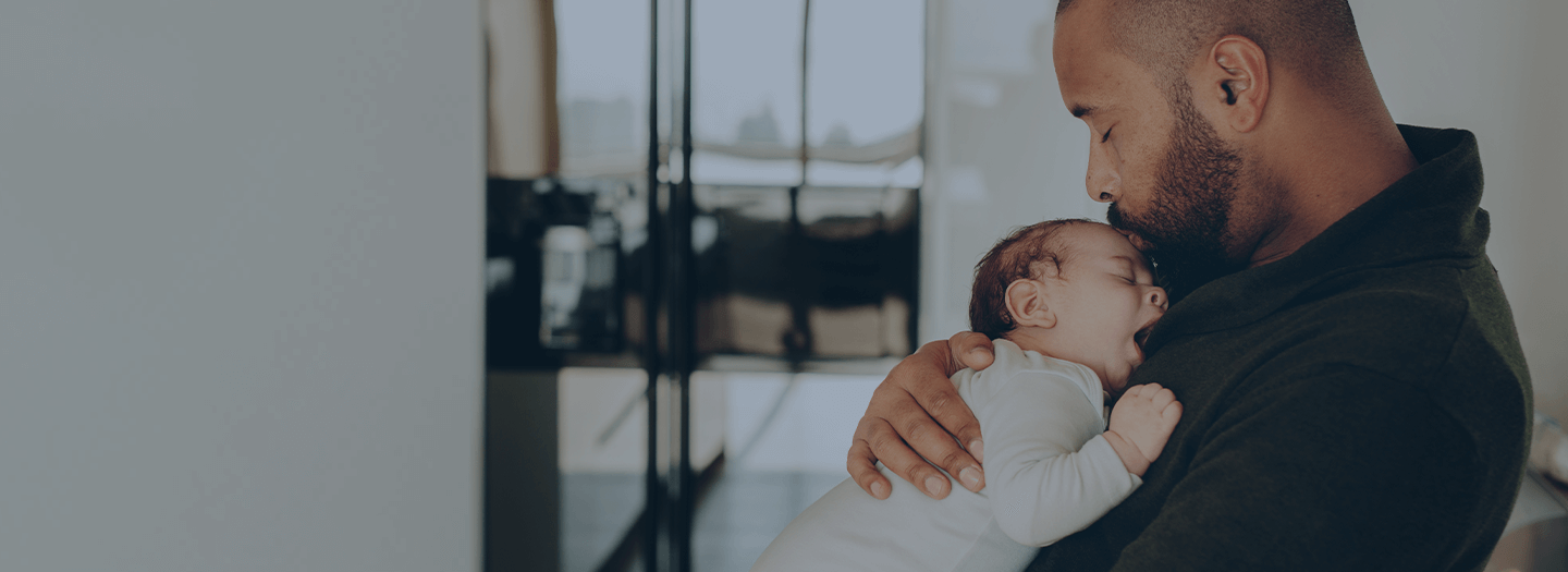 About banner Father holding infant and kissing its forehead