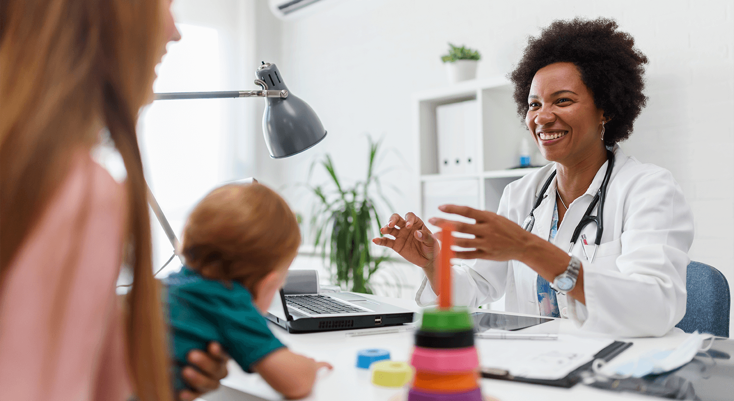 Mother and baby talking to female physician