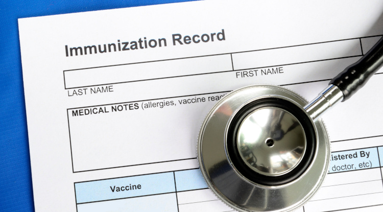vaccination record immunization record paperwork with stethoscope atop it