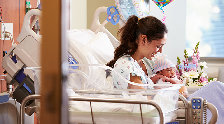 mother holding newborn infant in hospital bed