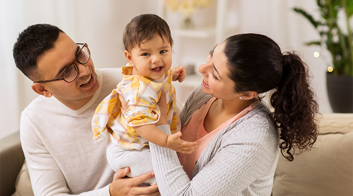 man and woman holding baby between them, smiling