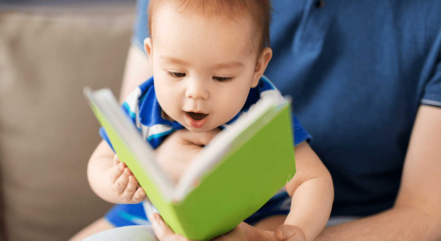 infant looking at green storybook